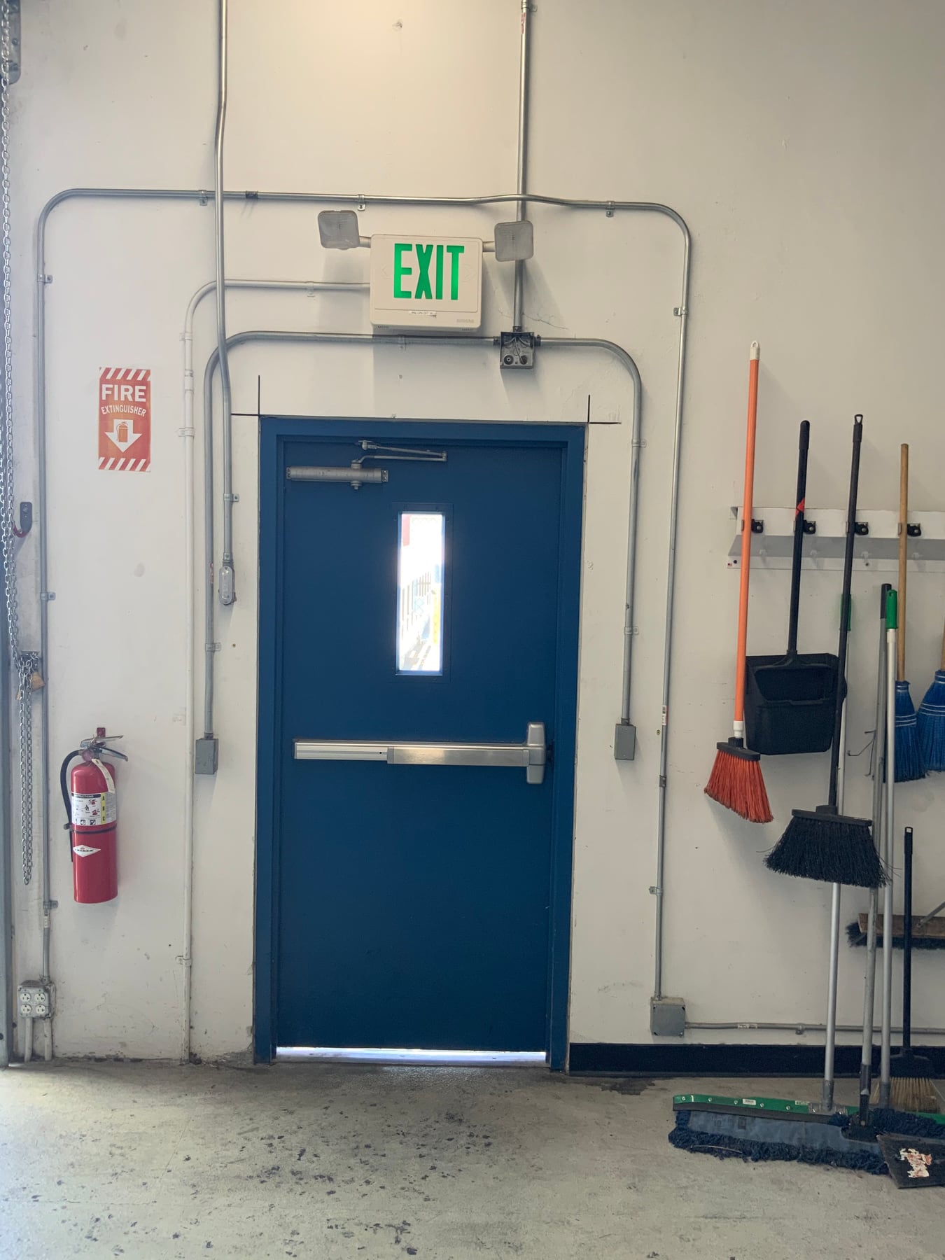 Daylight visible beneath a closed pedestrian door inside a warehouse