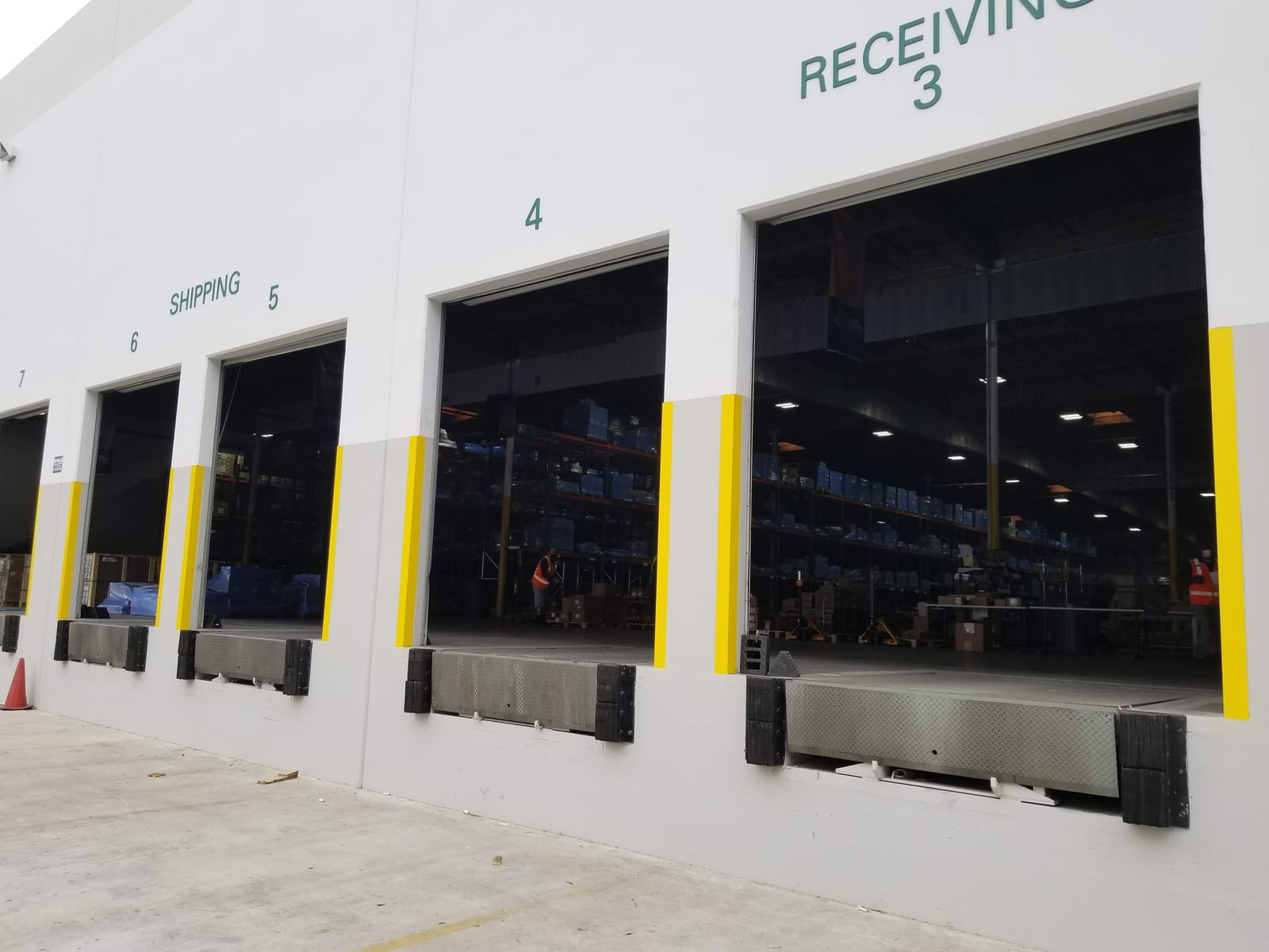 Warehouse shipping and receiving bays with dock levelers and yellow protective guards.